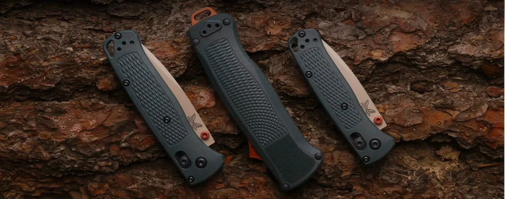 Three Benchmade folding knives with textured green handles and orange accents displayed on rugged pine bark.