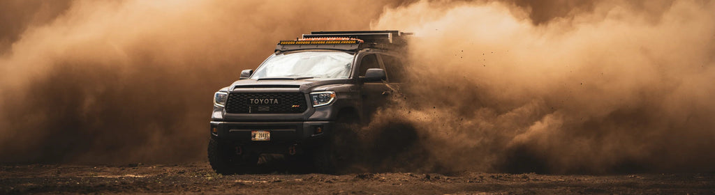 Toyota Tacoma kicking up dust in a rugged, adventurous landscape, symbolizing the dynamic energy of 2023.
