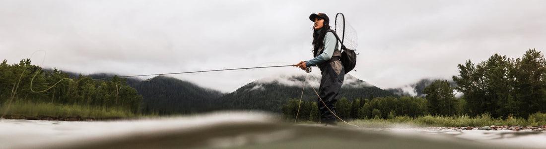 Keani Taketa fly fishing in a misty mountain river, showcasing her expert technique and calm focus.