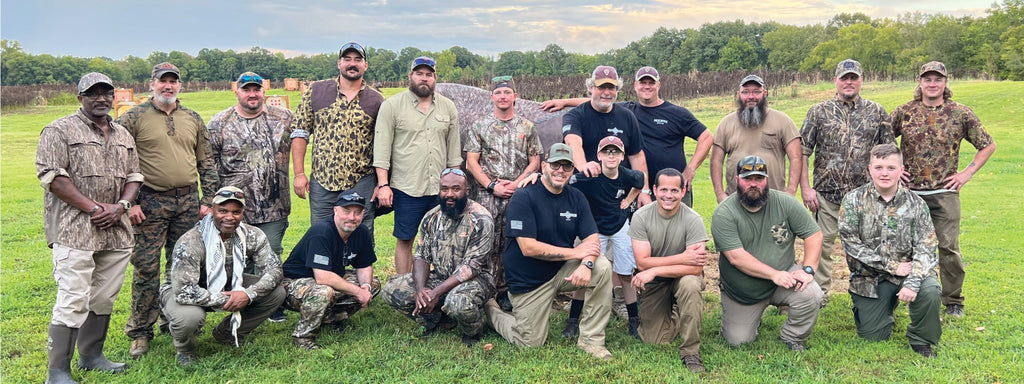 Diverse group of hunters in camouflage posing together outdoors, embodying strength and camaraderie within their community.