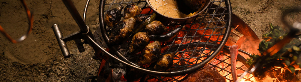 Charred turnips sizzle on a wire grate over glowing coals, capturing the rustic, smoky essence of outdoor cooking.