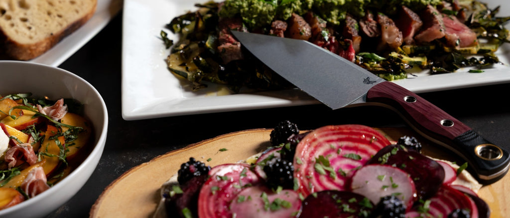 Vibrant beets, blackberries, and steak with a knife on dark table