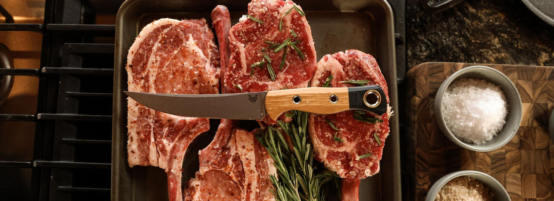 Wood-handled knife rests on seasoned raw lamb chops with rosemary, showcasing culinary precision and flavor.