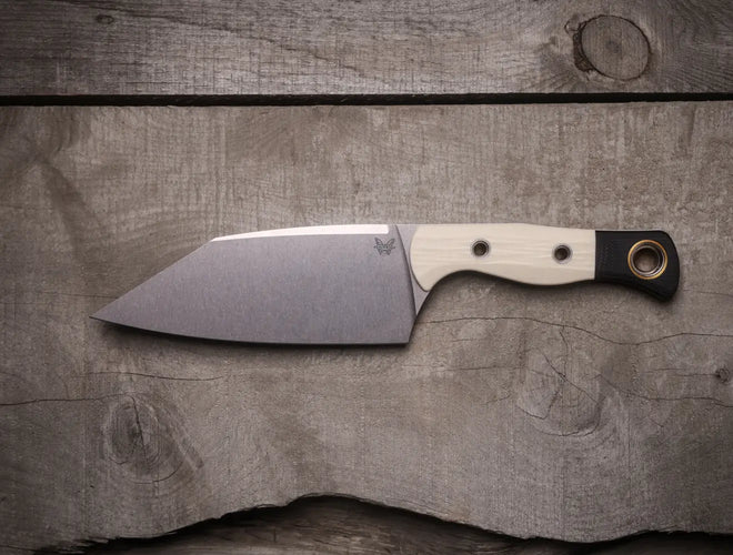 Benchmade knife with cream handle and black lanyard hole rests on weathered gray wooden planks.