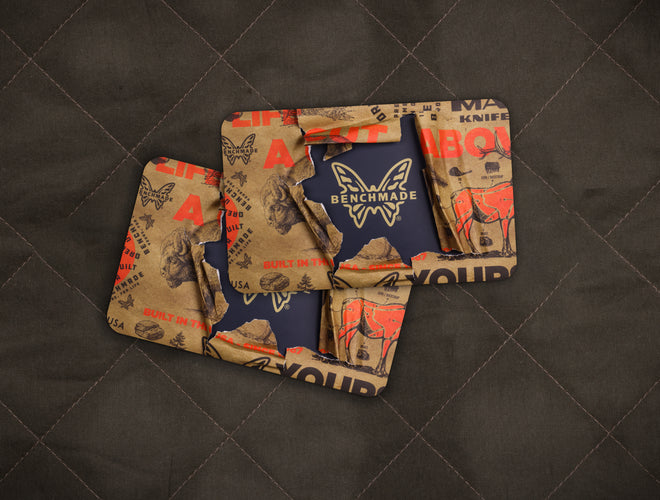 Torn Benchmade branded paper reveals navy logo card on dark quilted background, highlighting rugged outdoor brand aesthetic.