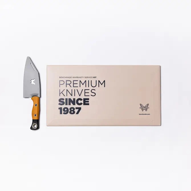 Silver knife with orange handle beside beige box reading "Premium Knives Since 1987" on white background.
