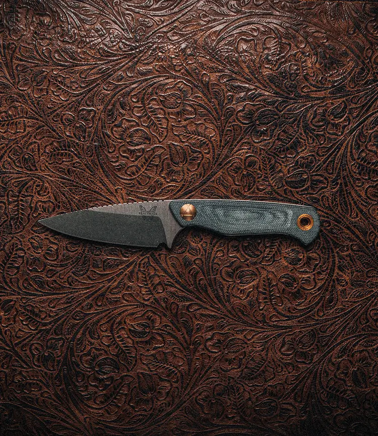 Fixed-blade knife with gray handle and bronze pins rests on embossed brown leather.