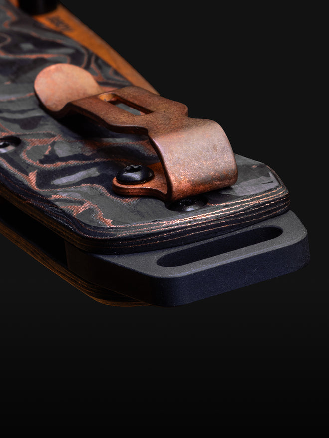 Close-up of a copper pocket clip on a marbled black-and-copper knife handle against a dark background.