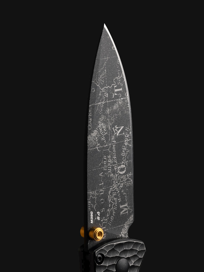 Knife blade etched with a map of Missouri, marked "M390 #4," against a black background.