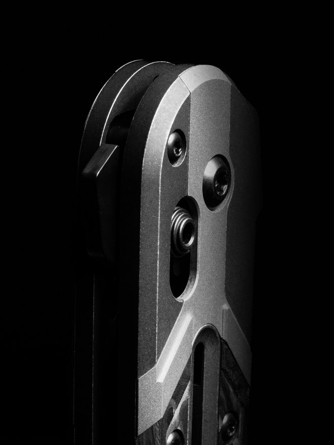Close-up of a silver metallic device with screws and slots, dramatically lit against a solid black background.