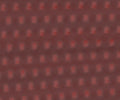 Red G10 knife handle scale with repeating textured pattern, close-up view of material surface.